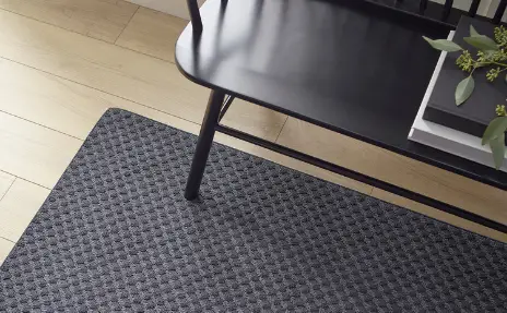 entryway with dark grey area rug over natural light hardwood floors